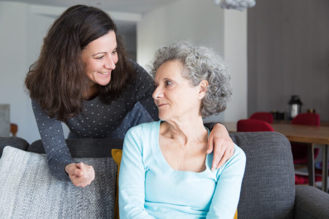 Smiling adult daughter supporting sad senior mother