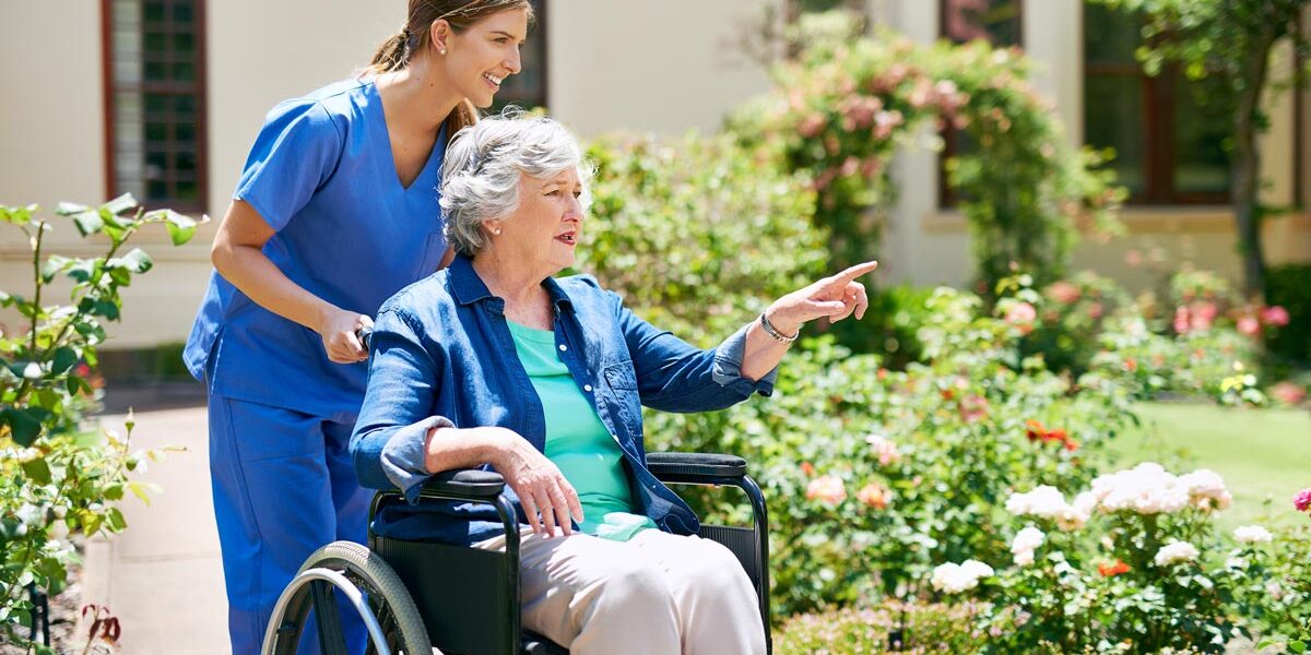dame-in-rolstoel-buiten-met-zorgprofessional