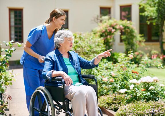 dame-in-rolstoel-buiten-met-zorgprofessional dame-in-rolstoel-buiten-met-zorgprofessional