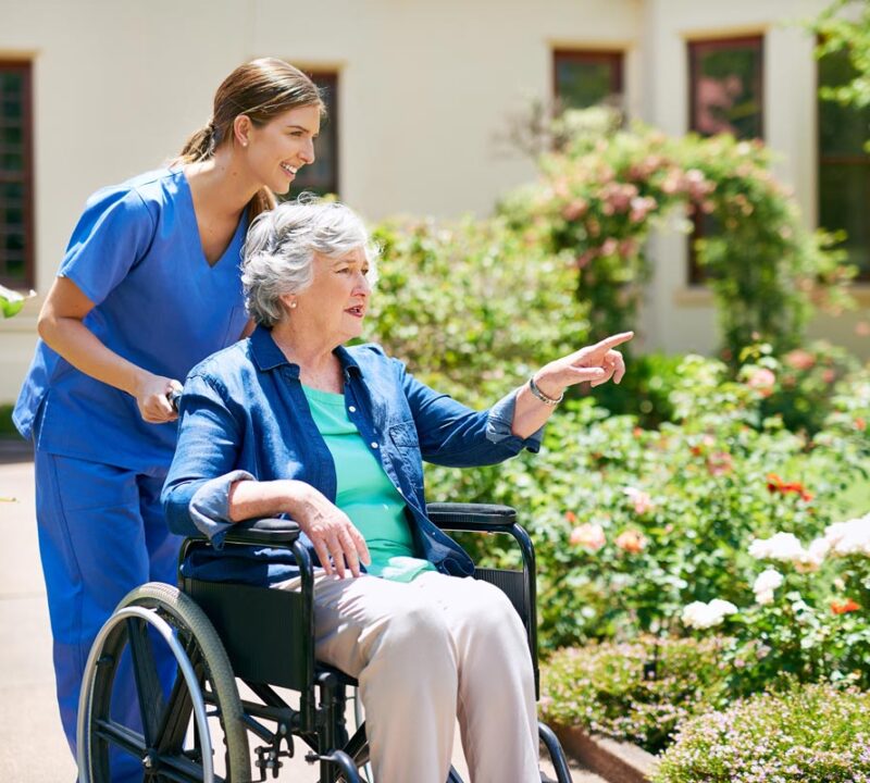 dame-in-rolstoel-buiten-met-zorgprofessional